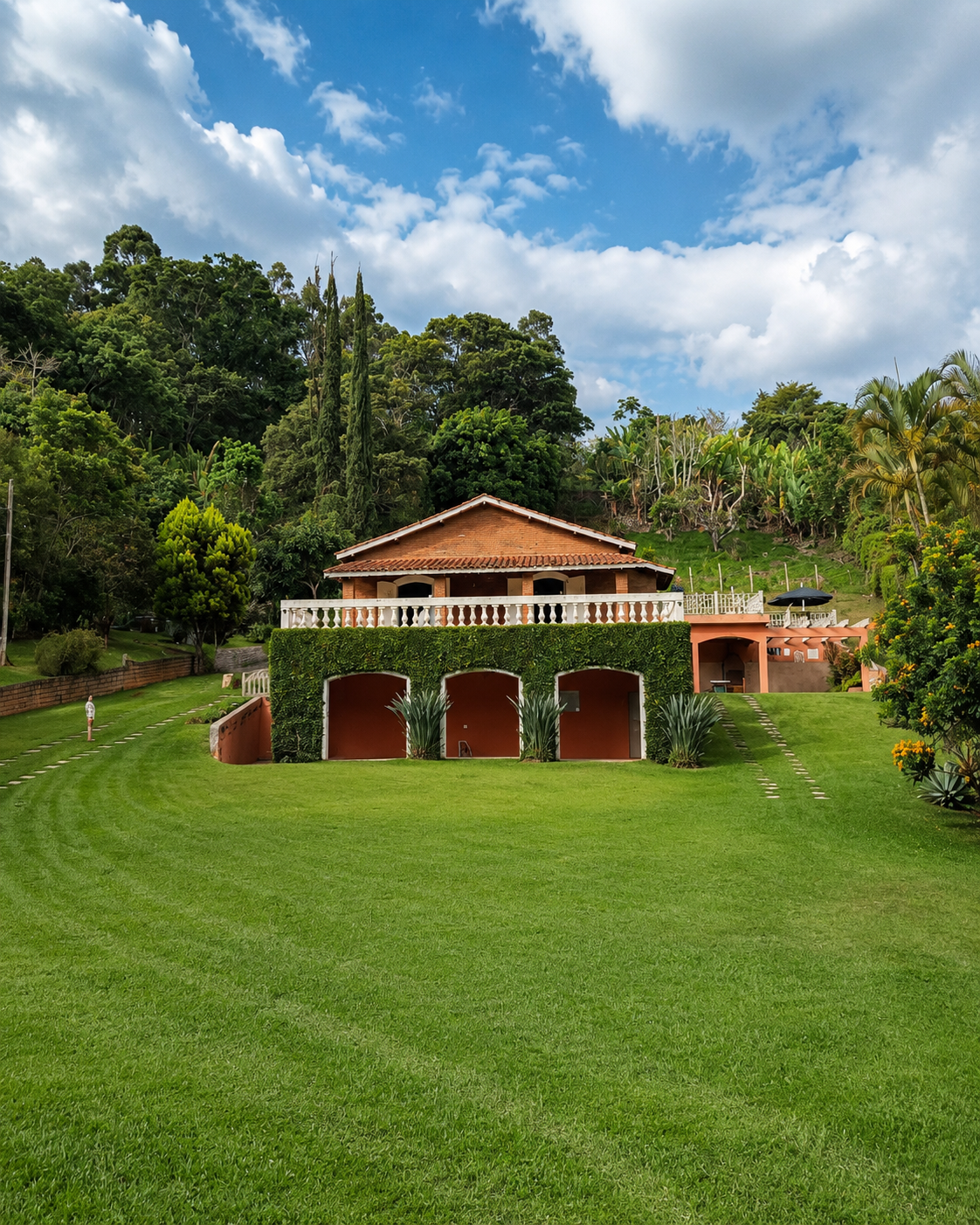Vista frontal da casa do Sítio Pomodoro cercada por jardins